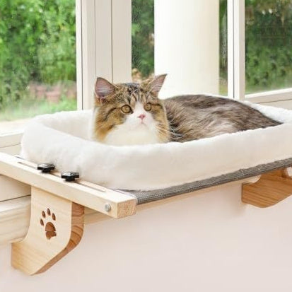 Cat relaxing on a white cushioned window hammock